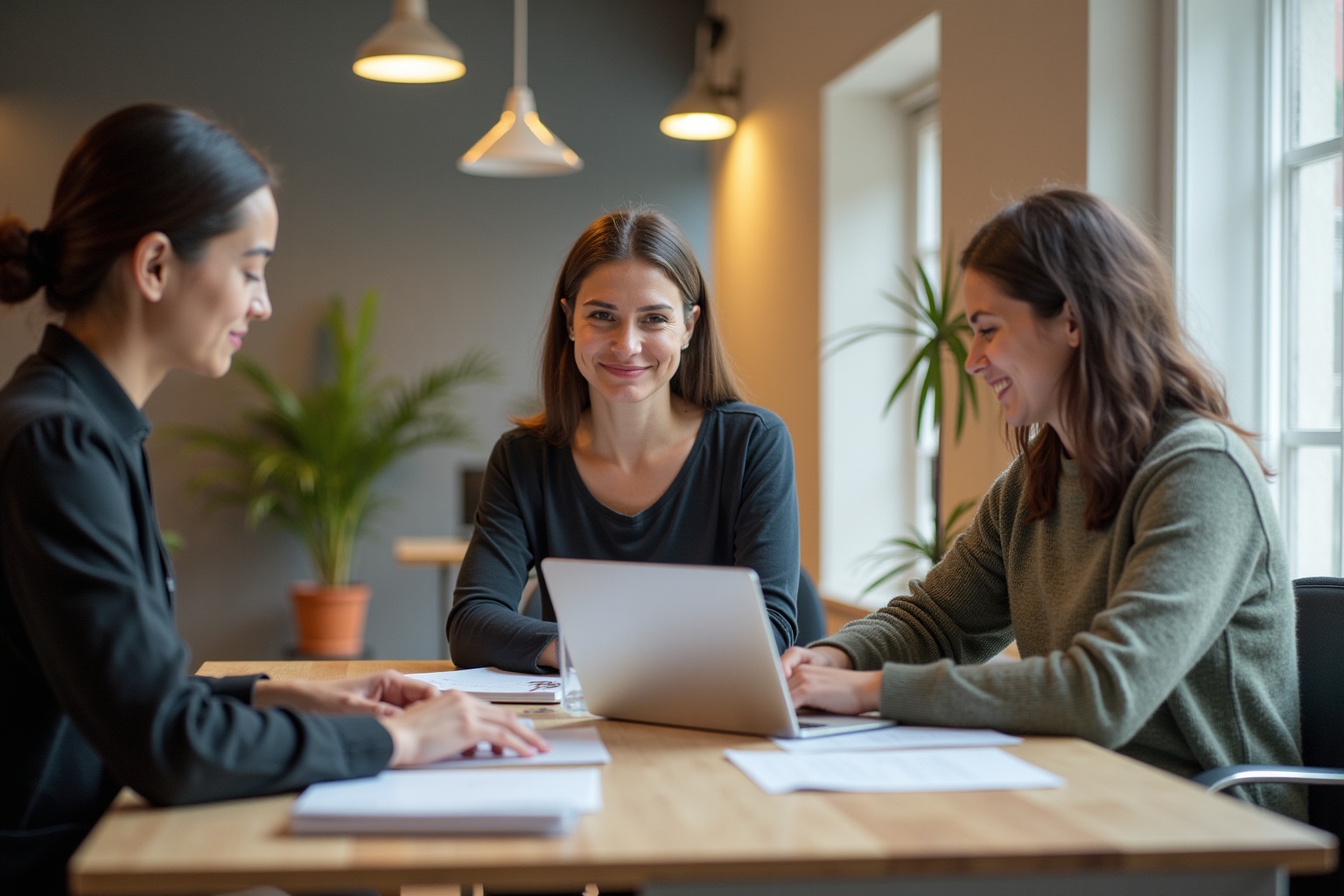 Trois femmes collaborant sur un projet dans un bureau lumineux.